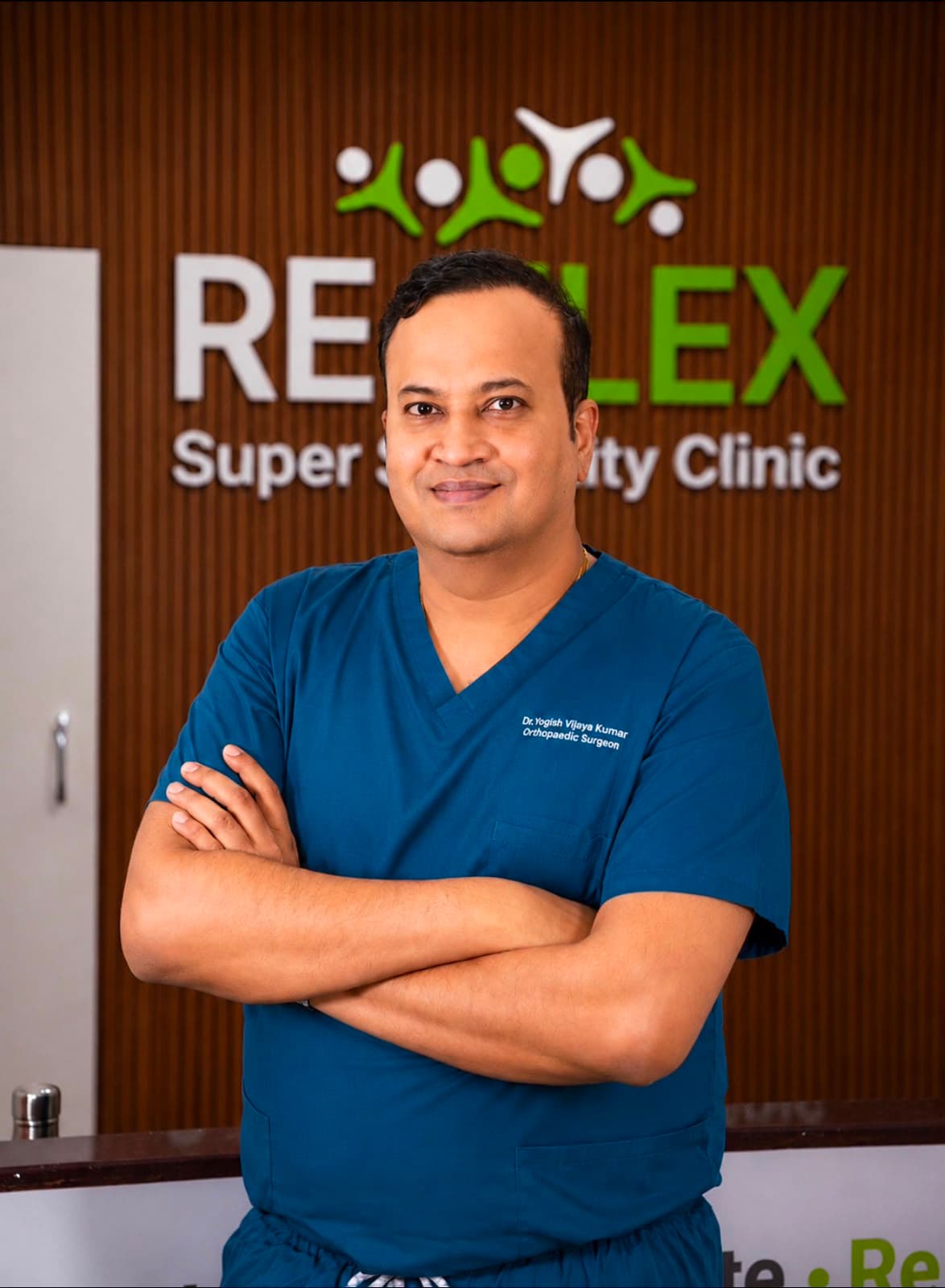 Dr. Yogish Vijaya Kumar in surgical scrubs at the reception of Re-Flex Super Speciality Clinic, Jayanagar