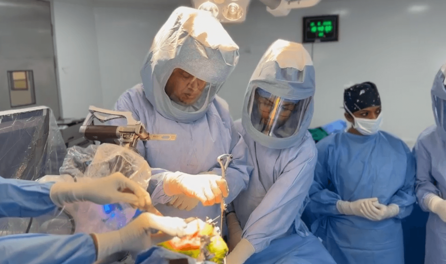 Dr. Yogish and his surgical team in hooded exhaust suits during a robot-assisted knee replacement